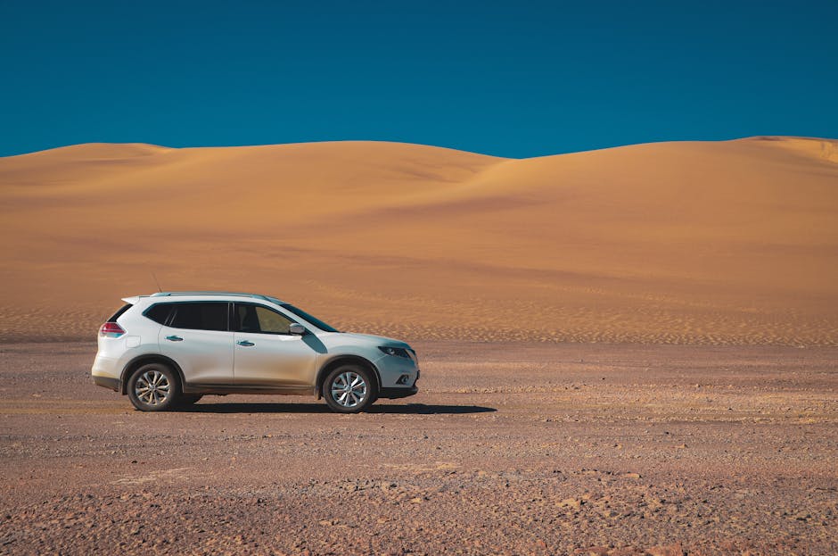 A white SUV drives through a vast desert landscape under a clear blue sky, showcasing adventure and exploration